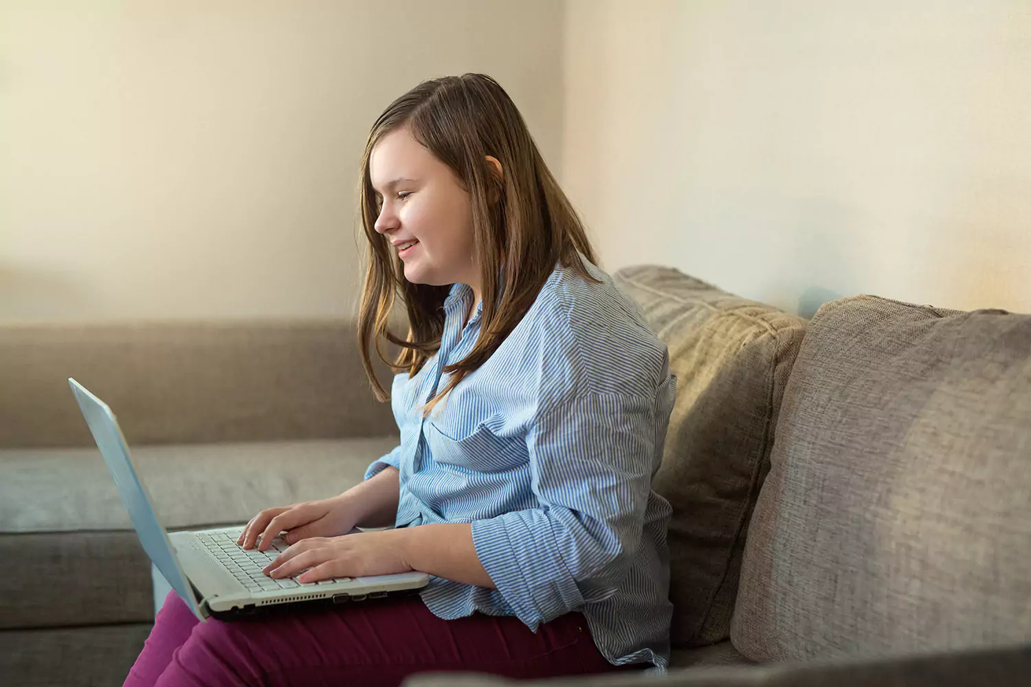 Young woman using a laptop to make a referral in the comfort of her own home